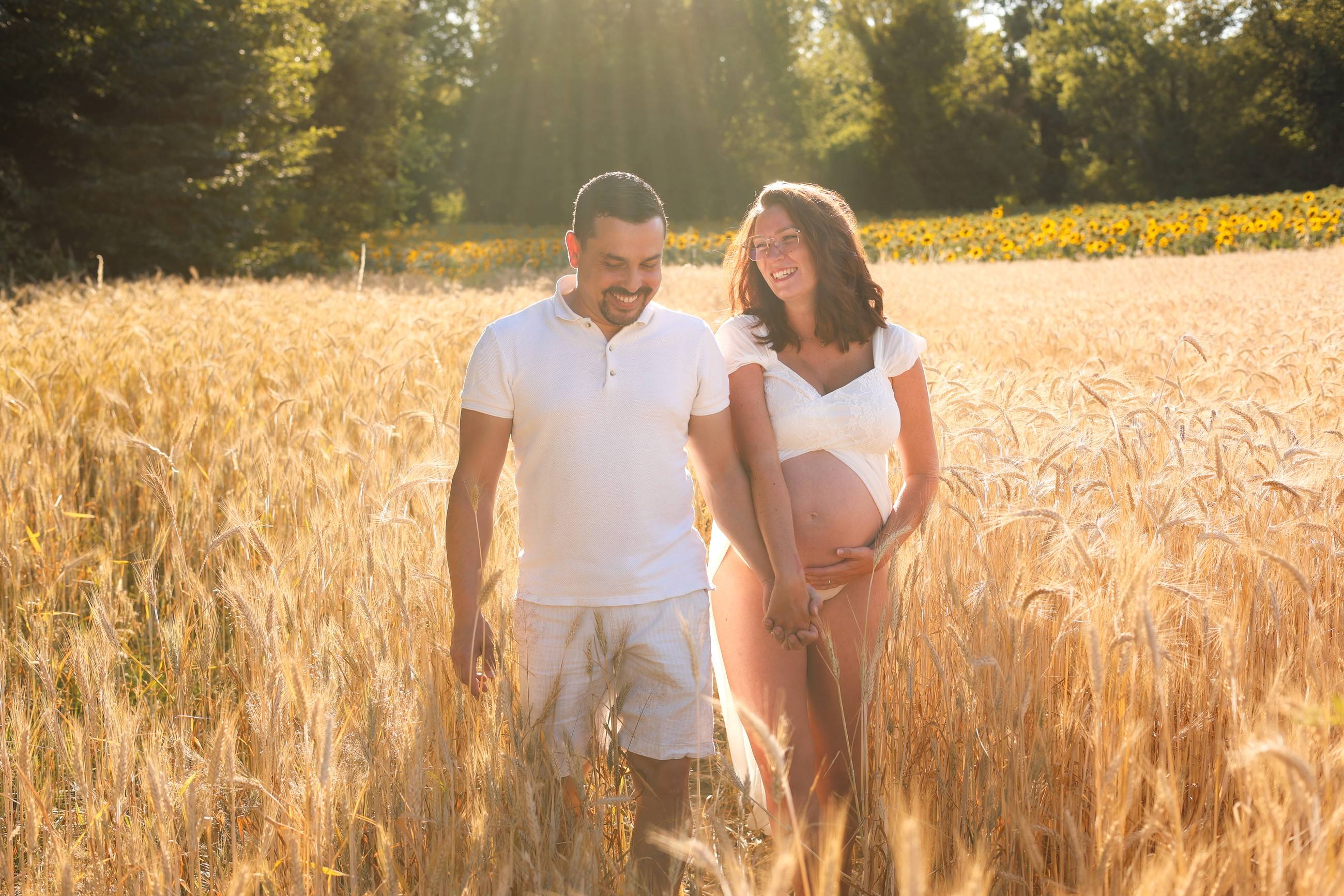 Futurs parents main dans la main dans un champ de blé doré près de Grenoble