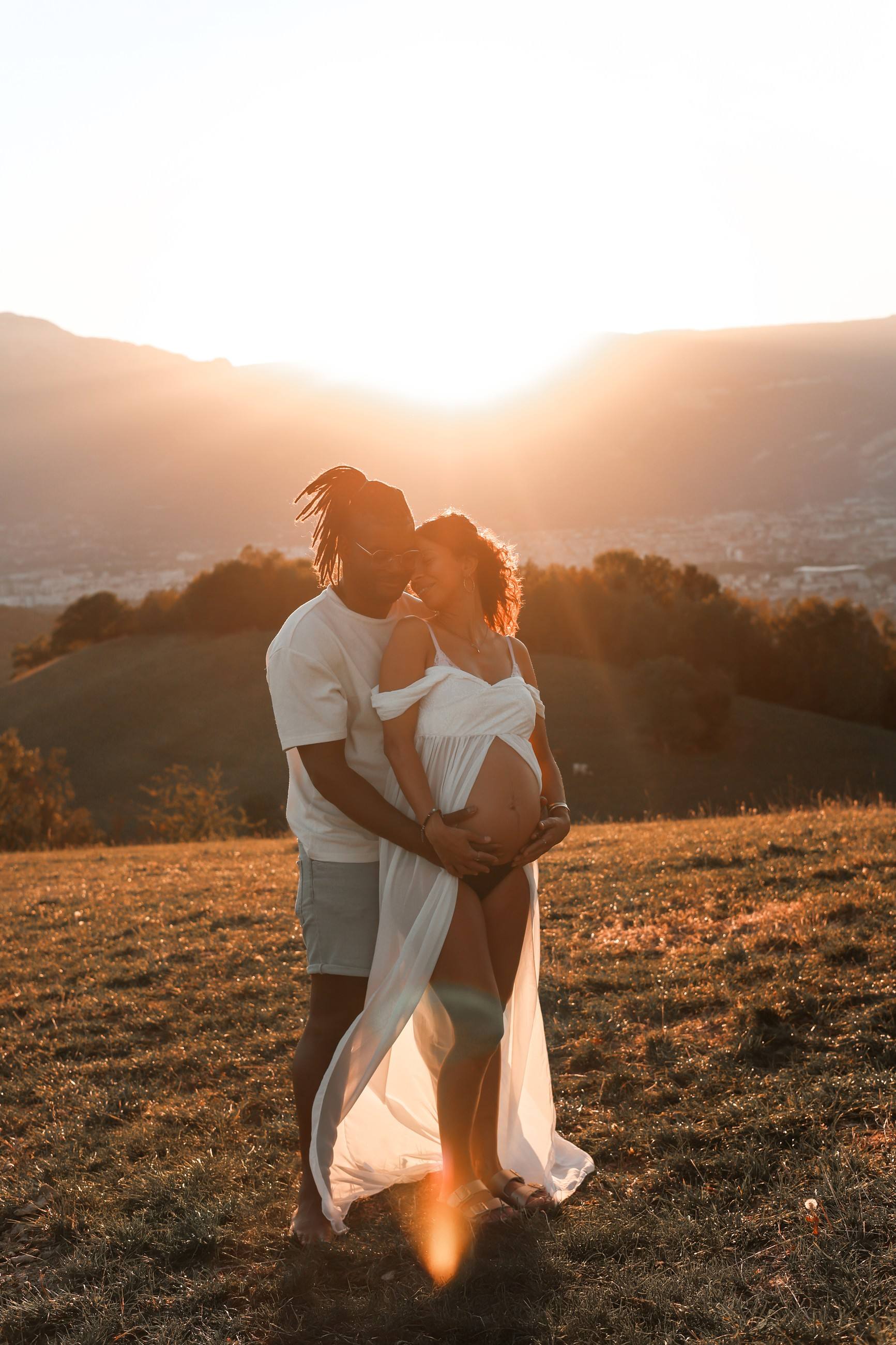 Couple enceinte sur une colline à contre-jour