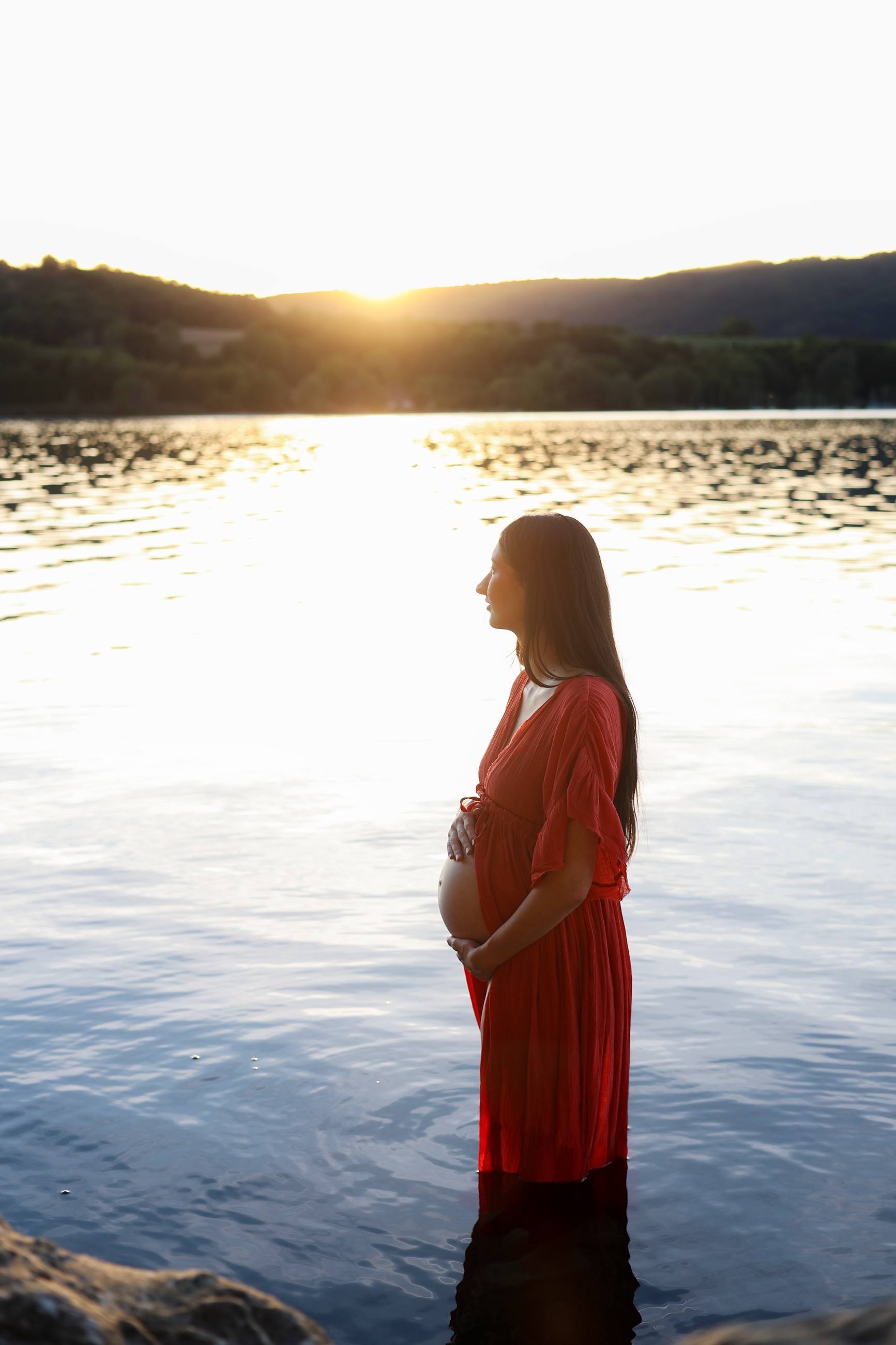 Femme enceinte dans un lac au coucher du soleil