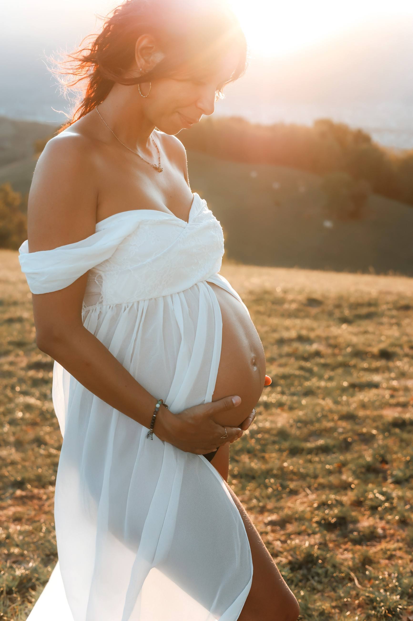 Femme enceinte en robe blanche sur une colline en Isère