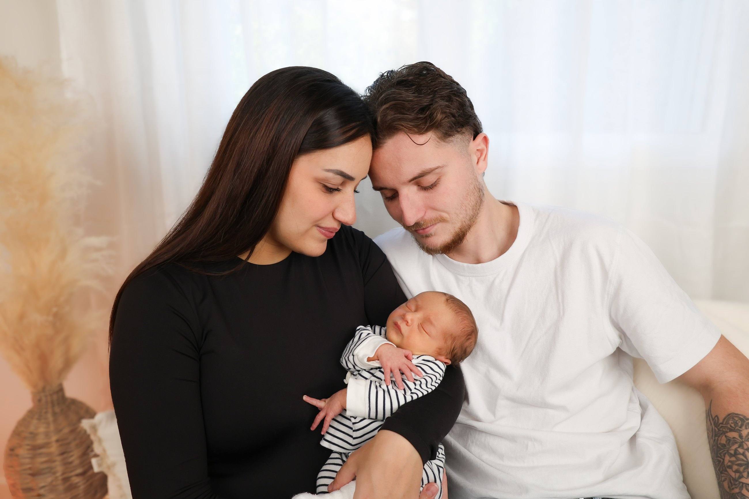 Parents et leur nouveau-né sur le canapé du studio